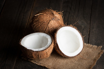 Ripe half cut coconut on a wooden background.  Coconut cream and oil.