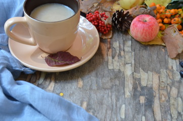Flat lay of composed cup with black coffee on wood table with ripe berries of rowan and dark foliage. Cappuccino or latte or tea on a vintage table. fallen leaves, ripe apples, berries. Copy space