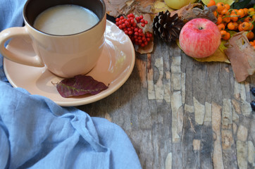 Flat lay of composed cup with black coffee on wood table with ripe berries of rowan and dark foliage. Cappuccino or latte or tea on a vintage table. fallen leaves, ripe apples, berries. Copy space