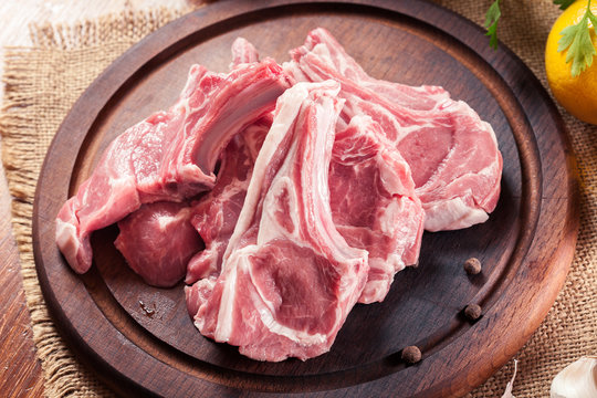 Raw fresh lamb chops on wooden cutting board