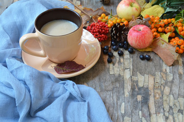 Flat lay of composed cup with black coffee on wood table with ripe berries of rowan and dark foliage. Cappuccino or latte or tea on a vintage table. fallen leaves, ripe apples, berries. Copy space
