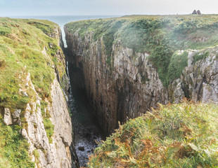 Fototapeta na wymiar Huntsman's Leap sheer-sided coastal chasm on the Pembrokeshire Coast in South Wales