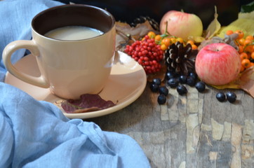 Flat lay of composed cup with black coffee on wood table with ripe berries of rowan and dark foliage. Cappuccino or latte or tea on a vintage table. fallen leaves, ripe apples, berries. Copy space