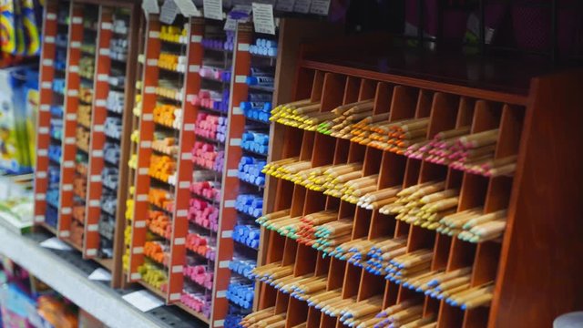 Purchase of stationery in the store. Many colorful tools and supplies on the shelf of a stationery shop