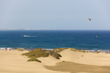 Parasailing aquatic sport in Playa del Ingles, Maspalomas. Sand dunes by the beach in Gran Canaria, Spain. Summer vacation, travel destination, tourist attraction concepts