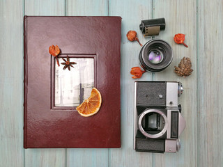 Flat lay photo. Album with photos from travel. Photo album with a camera and a lens on a light blue painted wooden background. Old photoalbum. Nostalgia