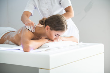 Fototapeta na wymiar Golden hands. Beautiful woman lying on massage table and enjoying spa procedure with cosmetic mask