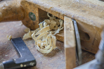 Very old wooden carpenter plane full of wooden remains left on the table.