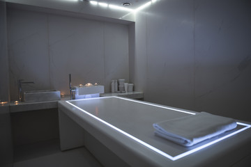 Peace and relaxation. Comfortable massage table with illumination. Soft folded towel lying on the desk
