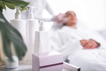 Good skincare. Close up of beauty tools on the table at cosmetologist cabinet. Woman in soft bathrobe getting injection on background