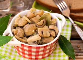 Pickled marinated button mushrooms with pepper and bay leaf