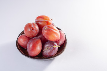 Group of ripe oval Victoria plums from England on white background with leaves