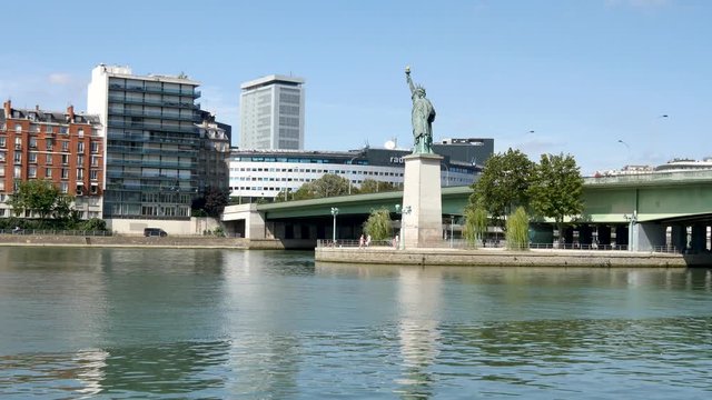 Statue of Liberty in Paris. The statue is smaller than the one in New York. It is located on a small island in the Seine. Front view. Pont de grenelle (parisian bridge) behind the statue.