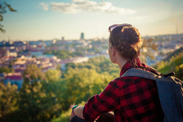 Young traveler woman tourist looking at a European city at sunset from a height, travel atmosphere, Vilnius, Lithuania