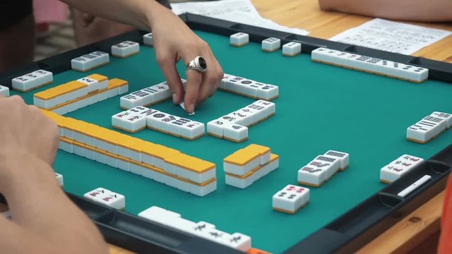 People Playing Mahjong Asian Tile-based Game. Table Gambling