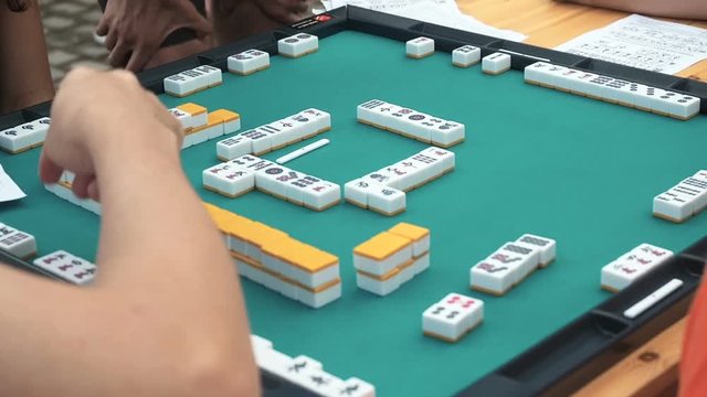People playing mahjong asian tile-based game. Table gambling