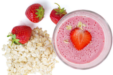 Glass of pink strawberry smoothie with oat flats. Top view