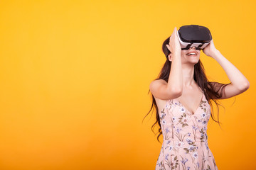 Girl plays vr game in virtual reality helmet in studio over yellow background. Studio portrait of girl playing mobile app on VR Glasses.