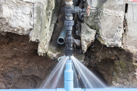 Water pipe break .Exposing a burst water main, focused on the spraying water and the pipe.