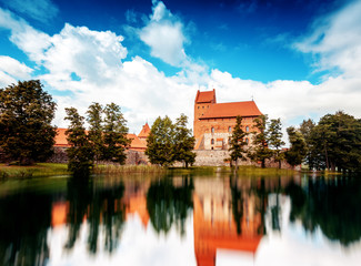 Obraz premium Medieval gothic Trakai Island Castle with stone walls and towers with red tiled roofs in Lake Galve, Lithuania