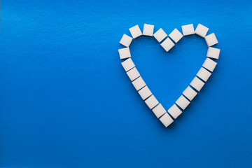 Obraz premium Heart made of cubes of sugar. blue background.