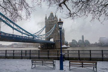 Fototapeta premium Blick auf die eingeschneite Tower Bridge am Ufer der Themse in London mit Schneefall zur Winterzeit