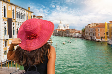 Touristin mit rotem Hut blickt von der Accademia Brücke auf den Canale Grande in Venedig, Italien - obrazy, fototapety, plakaty