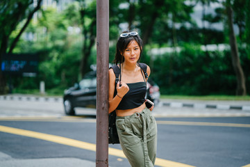 Image of a young, beautiful and attractive Chinese girl standing beside a street post.