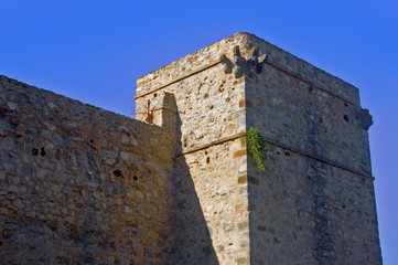 Fototapeta na wymiar Rectangular grey tower and wall, blue sky, summer