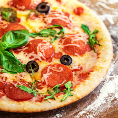 Hot pizza slice with Pepperoni, tomatoes, melting cheese on a rustic wooden table close up. Copy space