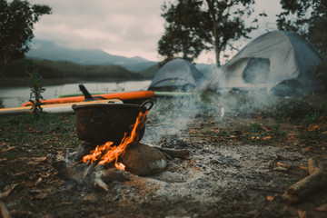 Camp and cooking in field conditions, boiling pot at the campfire on picnic in morning.  Cooking...