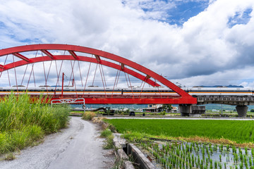Obraz premium Hualien, Taiwan-August 14, 2018: Beautiful Red Iron Bridge (Kecheng Bridge) And Morning Train Across The Rice Plantation At Yuli