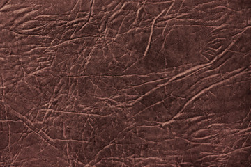 Colored skin texture, natural or faux brown leather background, closeup.