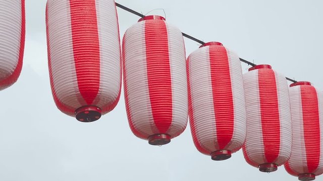 Paper red-white japanese lanterns Chochin hanging on cloudy sky background