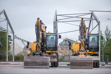 Multiple cars, excavators, trucks, loaders, concrete mixers and construction machinery in large...