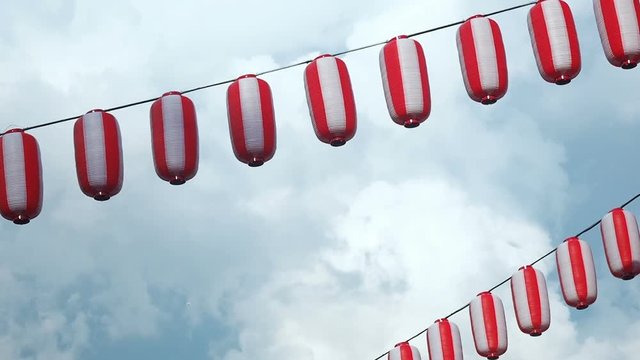 Paper red-white japanese lanterns Chochin hanging on blue cloudy sky background