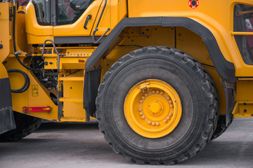 Macro shot of frontal excavator tire. Construction machinery in large parking lot in industrial...