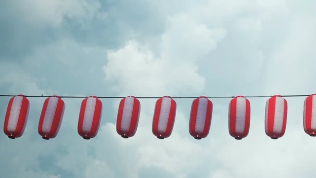 Paper red-white japanese lanterns Chochin hanging on blue cloudy sky background