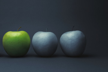 Close-up of green apple between gray fruit, still life