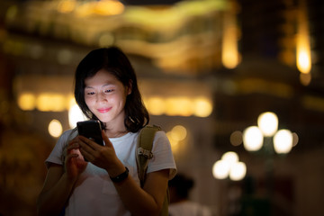 Young woman use smartphone on Macau street at night
