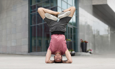 Professional yoga man doing headstand exercise outdoors
