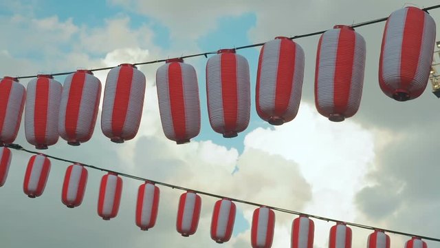 Paper red-white japanese lanterns Chochin hanging on blue cloudy sky background