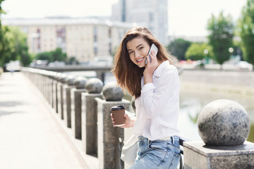 Beautiful smiling girl talking on smartphone outdoors