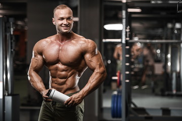 Obraz na płótnie Canvas Handsome strong bodybuilder athletic men pumping up muscles with dumbbells