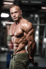 Naklejka na ściany i meble Handsome strong bodybuilder athletic men pumping up muscles with dumbbells