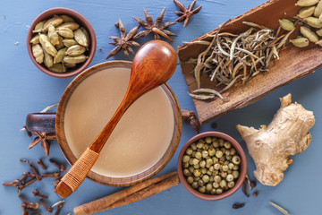 wooden spoon lies on a mug of Masala tea on a background of spices of cinnamon, cardamom, ginger, clove, tuba, sweet pepper. View from above. Close-up