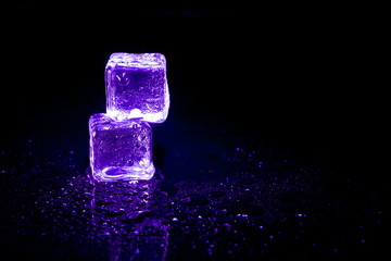 Purple ice cubes reflection on black table background.