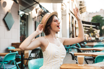 Cheerful woman in dress and straw hat waving away