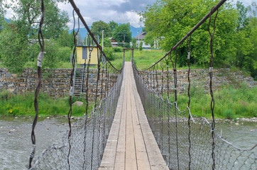 Suspension bridge across the mountain river. Carpathians Ukraine