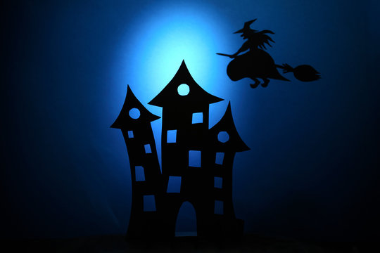 Scary castle silhouette,black paper bats and witch on broom flying on dark blue background. Halloween concept. Paper cut style.